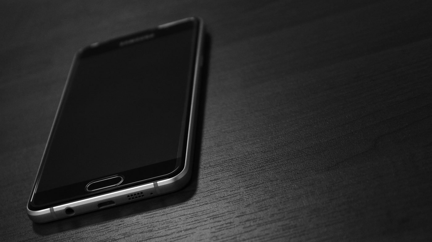 Black smartphone lying on a dark wooden table