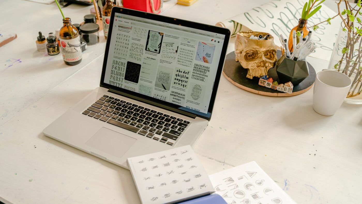 Designer's desk with a laptop, calligraphy book and lettering sheets
