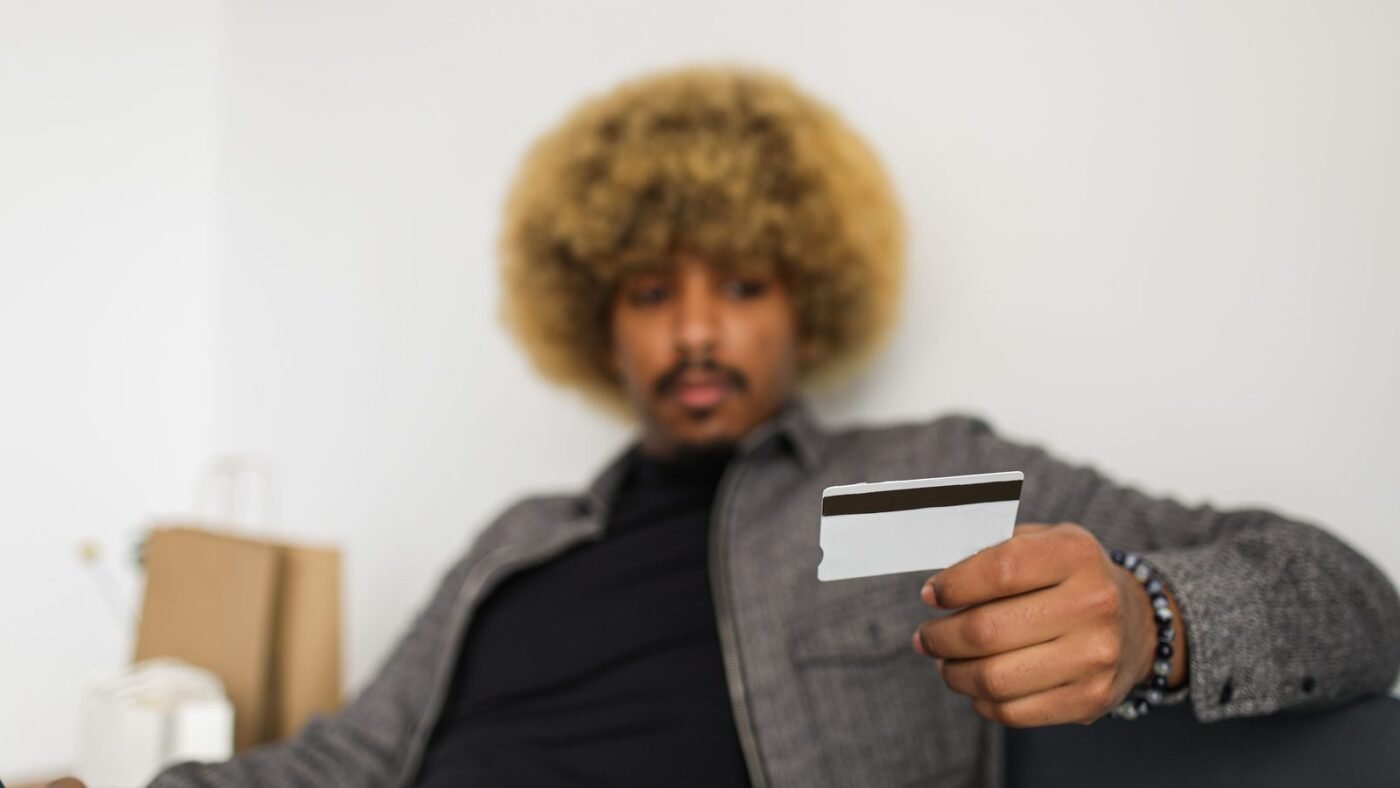 Young man with afro hair holding a credit card while shopping online