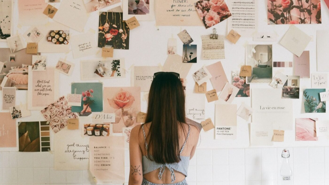 Woman standing in front of a wall covered with pinned photos and inspiration images