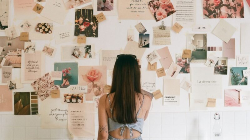 Woman standing in front of a wall covered with pinned photos and inspiration images