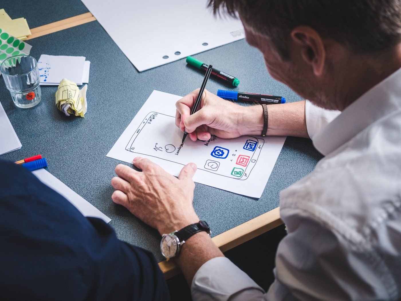 Designer sketching a mobile app layout on paper at a desk