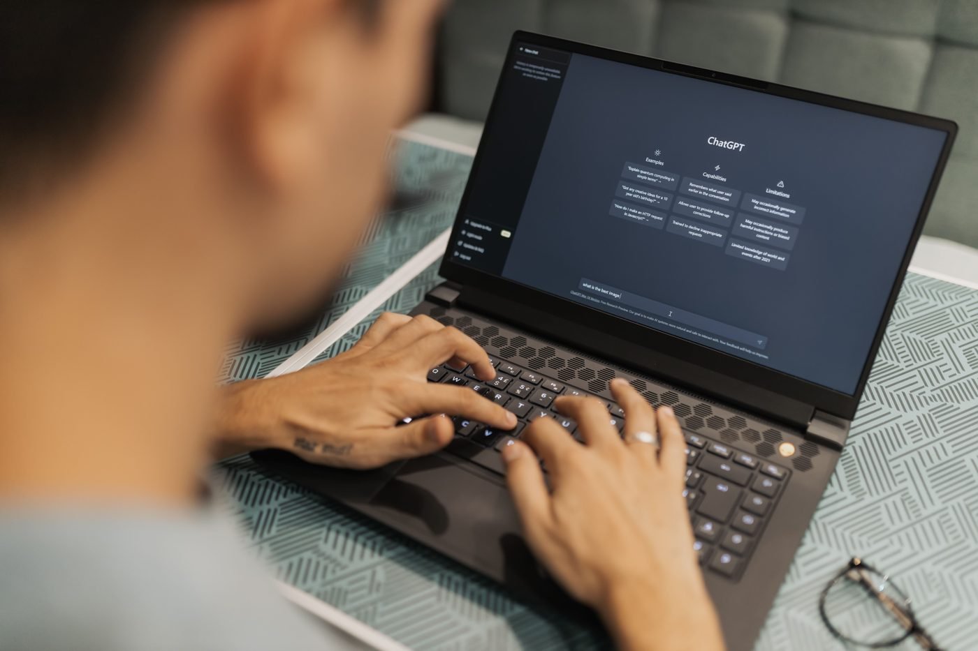 Person typing on a laptop showing an AI chatbot screen