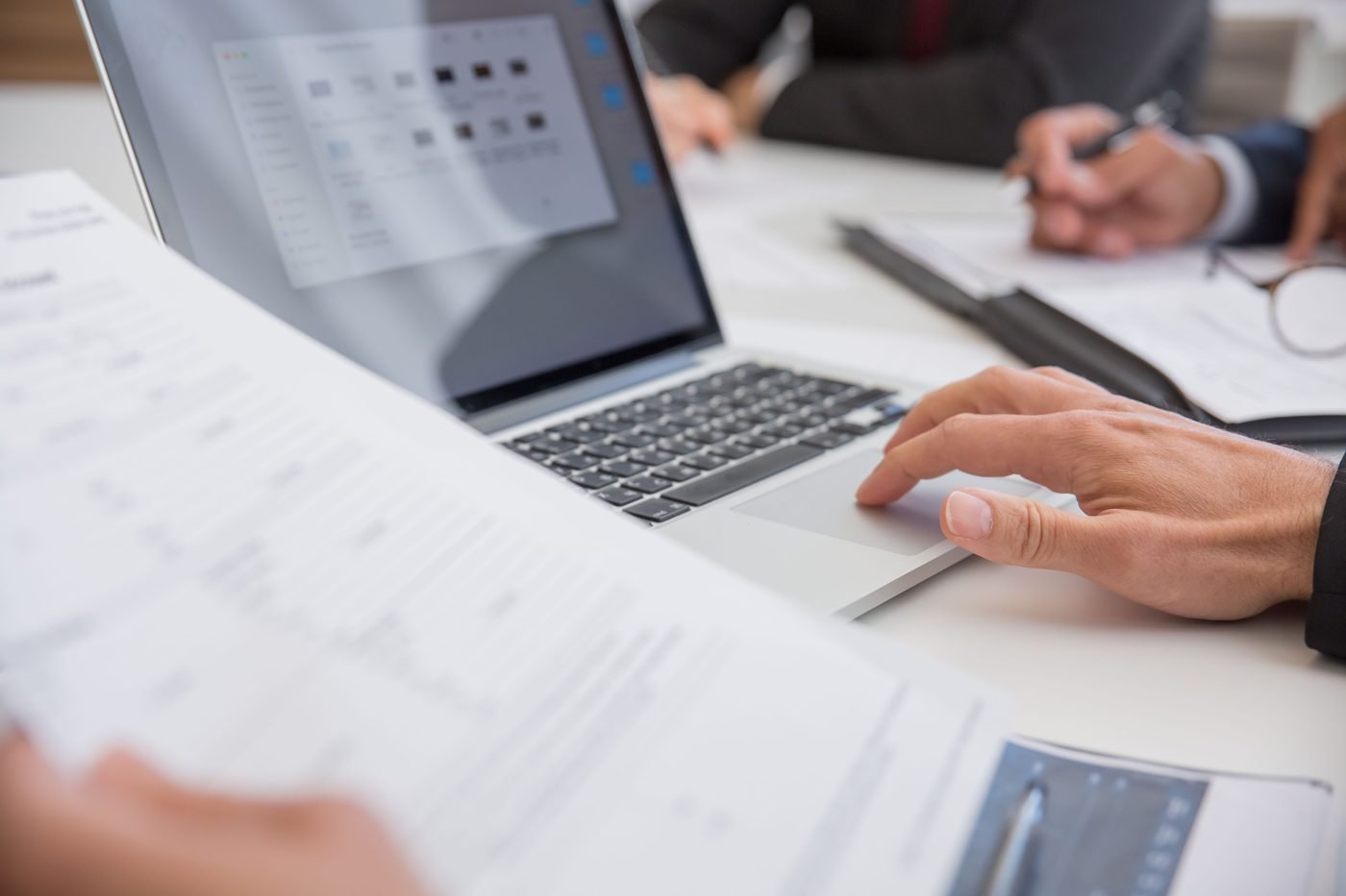 Hands working on documents next to a laptop in an office