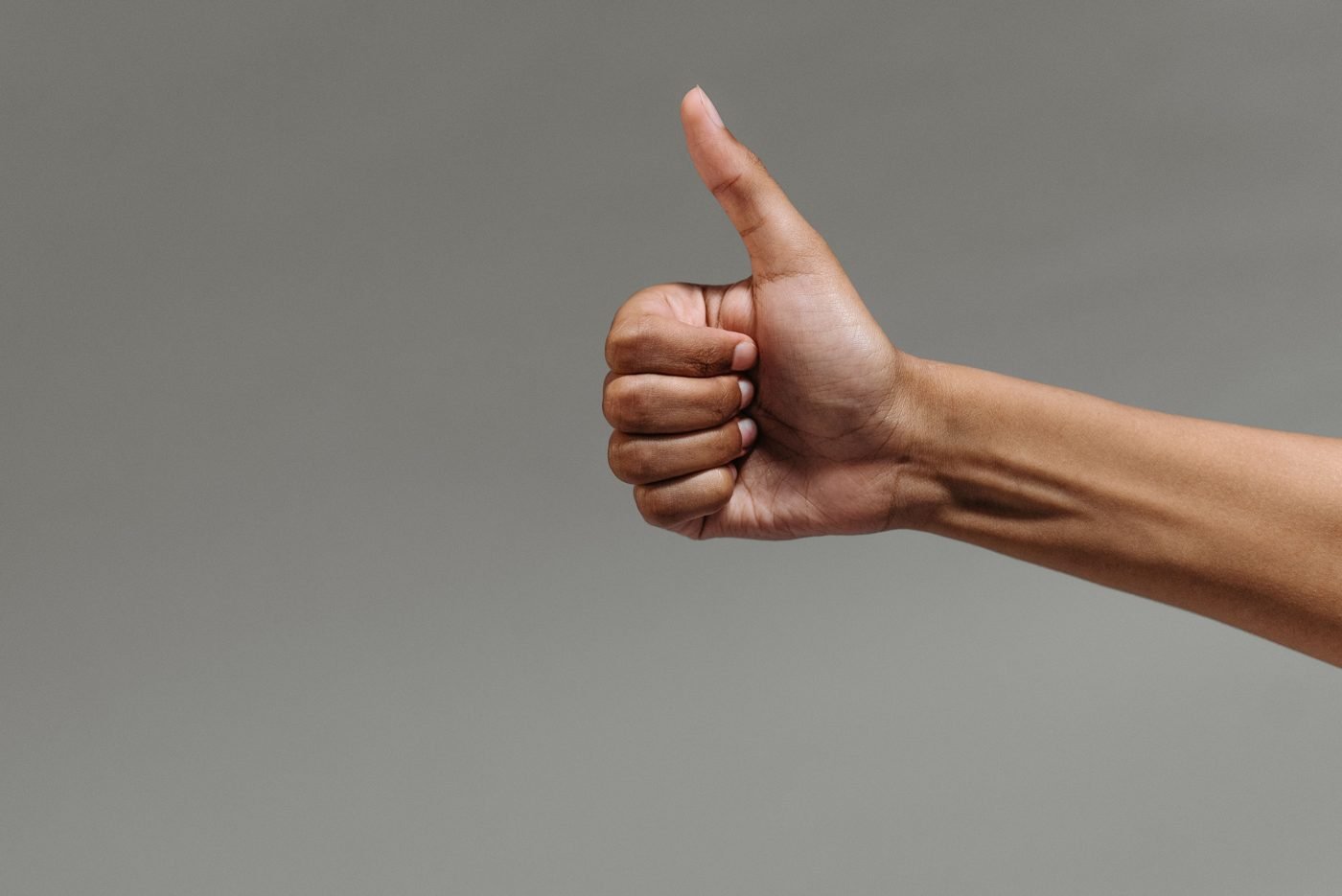 A hand giving a thumbs-up against a gray background