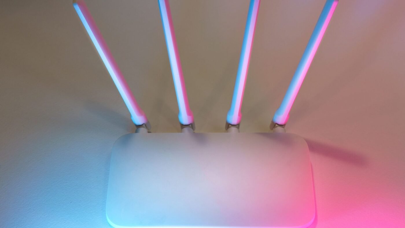 White wireless router with four antennas glowing in soft light