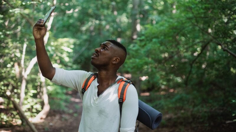 Hiker in a forest holding a smartphone up in the air
