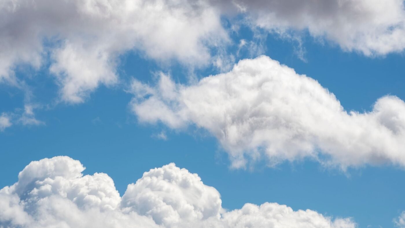 Soft white clouds drifting across a bright blue daytime sky