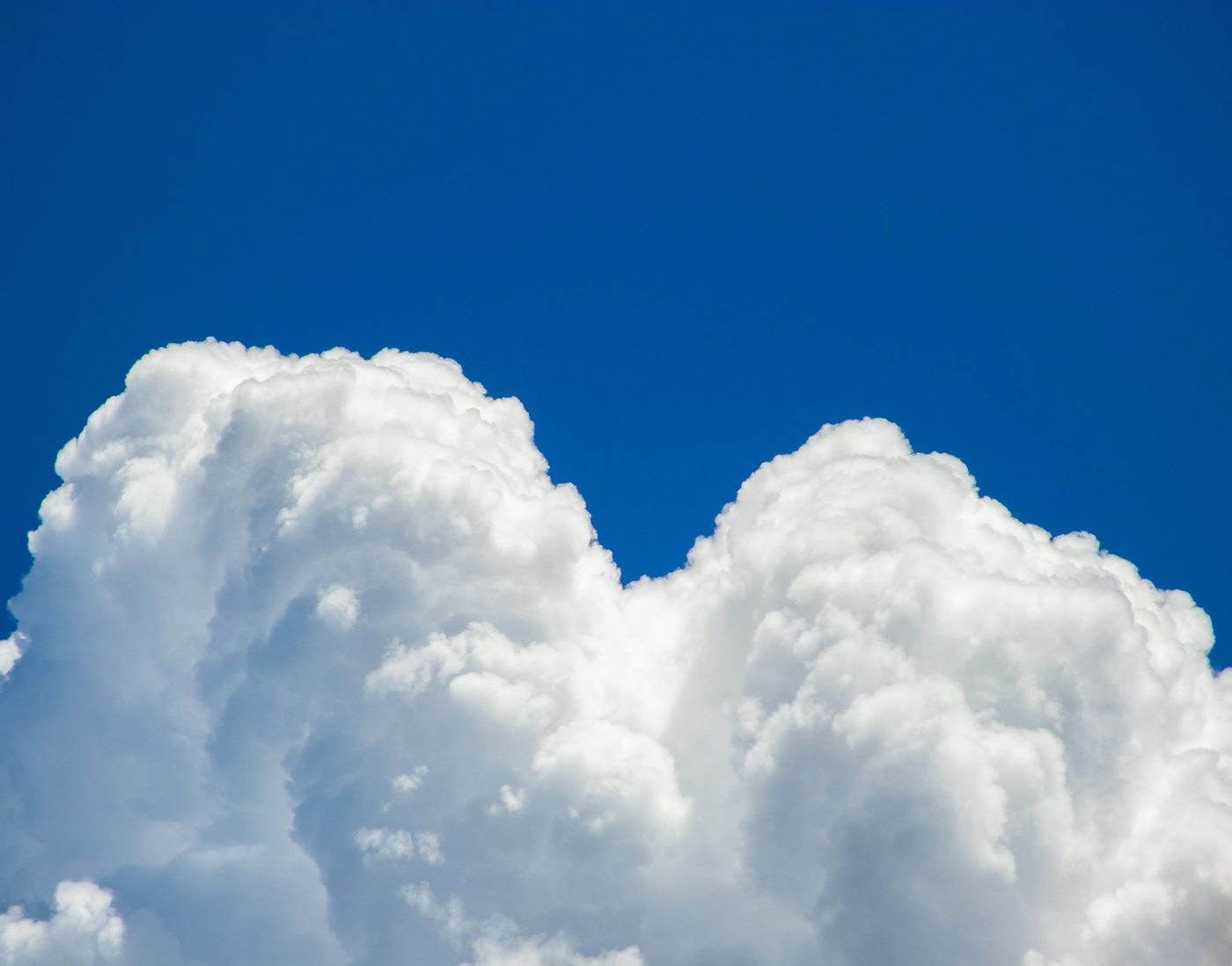 Tall white cumulus clouds against a deep blue sky